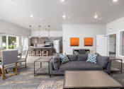 Thumbnail 33 of 35 - A modern living room with a grey couch and a wooden coffee table.