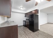 Thumbnail 4 of 35 - A kitchen with a black fridge and wooden cabinets.