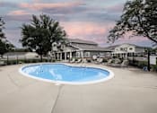 Thumbnail 12 of 35 - A large outdoor swimming pool surrounded by a fence and a house in the background.