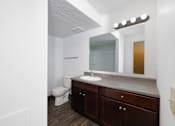 Thumbnail 9 of 35 - A bathroom with a toilet, sink, and mirror.