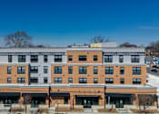 Thumbnail 5 of 50 - A large multi-story building with a flat roof and a yellow section on the top floor.