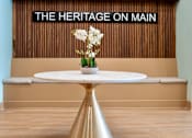 Thumbnail 9 of 50 - A white table with a gold pedestal stands in front of a wall with a sign that reads "The Heritage on Main.".