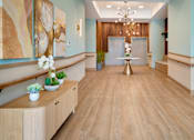 Thumbnail 10 of 50 - A hallway with a wooden floor and a chandelier hanging from the ceiling.