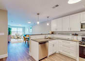 Thumbnail 23 of 50 - A kitchen with white cabinets and a wooden island.