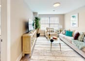 Thumbnail 20 of 50 - A living room with a white couch and a television on a wooden stand.