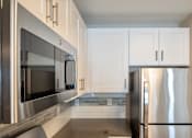 Thumbnail 31 of 50 - A modern kitchen with a stainless steel refrigerator and microwave.