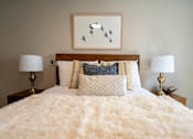 Thumbnail 41 of 50 - A bed with a white fluffy cover and a picture of birds on the wall.