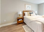 Thumbnail 39 of 50 - A bedroom with a large bed and a nightstand with a lamp.