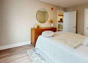 Thumbnail 40 of 50 - A bedroom with a bed, nightstand, and mirror.