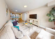 Thumbnail 45 of 50 - A living room with a white couch and a glass coffee table.