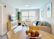Thumbnail 46 of 50 - A living room with a white couch and a wooden table.