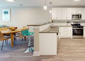 Thumbnail 44 of 50 - A kitchen with white cabinets and a wooden table.