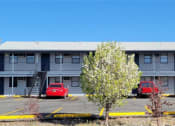Thumbnail 4 of 8 - an apartment building with cars parked in a parking lot