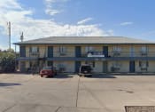 Thumbnail 1 of 8 - an apartment building with cars parked in front of it
