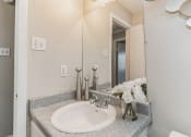 Thumbnail 15 of 19 - a bathroom with a sink and a mirror and a vase of flowers