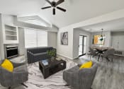 Thumbnail 1 of 11 - a living room with couches and a table and a ceiling fan