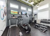 Thumbnail 19 of 23 - gym with exercise equipment and tv at the district flats apartments in lenexa