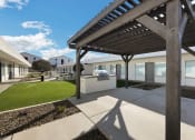 Thumbnail 12 of 17 - a covered patio with a grill and a lawn in front of a building