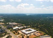 Thumbnail 64 of 65 - an aerial view of a campus with a large building and a highway at Birdie on Woodland Greens, Austin, 78726