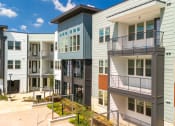 Thumbnail 13 of 65 - a row of new apartment buildings with stairs and balconies at Birdie on Woodland Greens, Austin, Texas