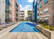 Thumbnail 6 of 37 - a swimming pool with chaise lounge chairs and palm trees in front of an apartment building at Republic at Alamo Heights, Texas