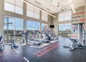Thumbnail 4 of 37 - a gym with cardio machines and windows with a view of the city at Republic at Alamo Heights, San Antonio, TX