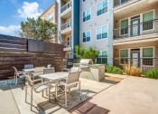 Thumbnail 20 of 37 - a patio with a table and chairs and a fire pit in front of an apartment building at Republic at Alamo Heights, San Antonio, 78209