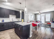 Thumbnail 29 of 37 - a kitchen and living room with dark cabinets and a white table with red chairs at Republic at Alamo Heights, Texas