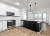 Thumbnail 30 of 65 - a white and black kitchen with white cabinets and a wood floor at Birdie on Woodland Greens, Austin, Texas