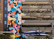 Thumbnail 8 of 30 - Outdoor courtyard with colorful mural and dining area at THE'68 Apartments, Texas