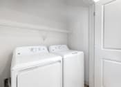 Thumbnail 44 of 65 - a white laundry room with two washes and a dryer at Birdie on Woodland Greens, Austin, TX