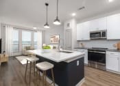 Thumbnail 34 of 65 - a kitchen with white cabinets and a large island with two stools at Birdie on Woodland Greens, Austin, 78726