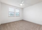 Thumbnail 39 of 65 - an empty room with two windows and a ceiling fan at Birdie on Woodland Greens, Austin, TX