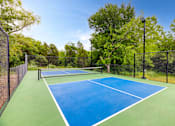 Thumbnail 48 of 72 - a tennis court with a fenced in area and a blue and green at Radius on Grove, Austin, TX, 78741
