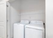 Thumbnail 46 of 65 - a white laundry room with two washes and a dryer at Birdie on Woodland Greens, Austin, 78726