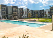 Thumbnail 56 of 65 - an outdoor pool with an apartment building in the background at Birdie on Woodland Greens, Texas