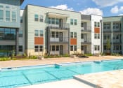 Thumbnail 57 of 65 - an image of a swimming pool in front of an apartment building at Birdie on Woodland Greens, Austin, 78726