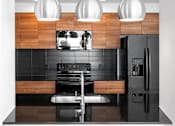 Thumbnail 22 of 30 - Modern kitchen with wood cabinetry and black backsplash at THE'68 Apartments, San Antonio, Texas