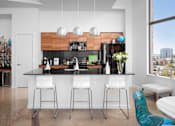 Thumbnail 24 of 30 - Modern kitchen with breakfast bar and pendant lights at THE'68 Apartments, San Antonio, TX 78205
