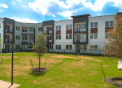 Thumbnail 61 of 65 - an exterior view of an apartment building with grass and trees at Birdie on Woodland Greens, Austin, TX
