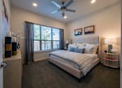 Thumbnail 22 of 41 - A bedroom with a large bed, a ceiling fan, and a window with curtains.