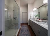 Thumbnail 35 of 41 - A bathroom with a glass shower door and a marble countertop.