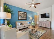 Thumbnail 37 of 59 - a living room with a blue accent wall and a ceiling fan at Alvista Round Rock, Round Rock, TX