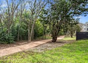 Thumbnail 42 of 72 - a path in a park with trees and a building in the background at Radius on Grove, Texas, 78741