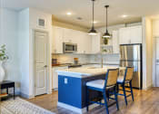 Thumbnail 27 of 65 - a kitchen with a blue island and white cabinets at Birdie on Woodland Greens, Texas 78726