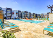 Thumbnail 53 of 65 - an outdoor pool with lounge chairs and a building with apartments in the background at Birdie on Woodland Greens, Texas