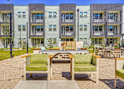 Thumbnail 52 of 65 - A patio with a table and chairs in front of apartment buildings.