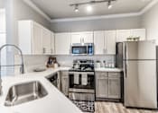 Thumbnail 7 of 36 - A modern kitchen with a stainless steel refrigerator, microwave, and oven at Rosemary Apartments, Conroe, TX