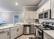 Thumbnail 8 of 36 - A modern kitchen with a stainless steel dishwasher and oven at Rosemary Apartments, Conroe, Texas