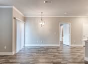 Thumbnail 9 of 36 - A room with a wooden floor and a chandelier hanging from the ceiling at Rosemary Apartments, Conroe